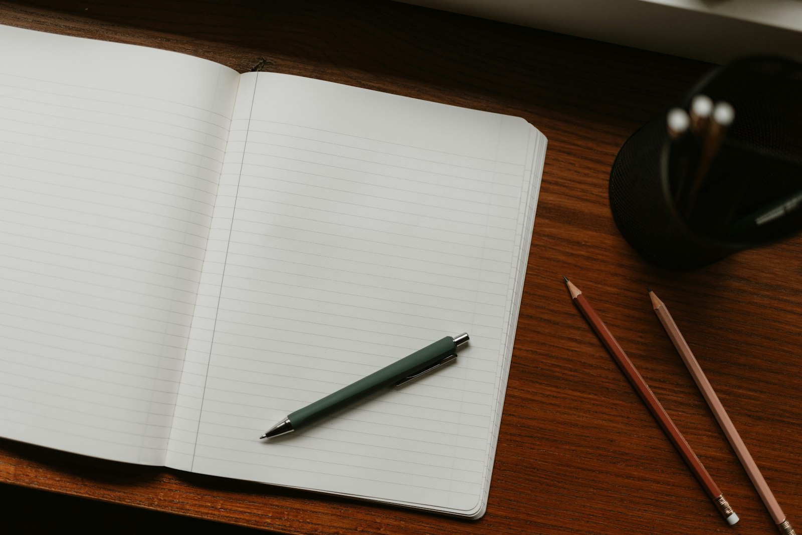 Cuaderno abierto con un bolígrafo sobre un escritorio de madera